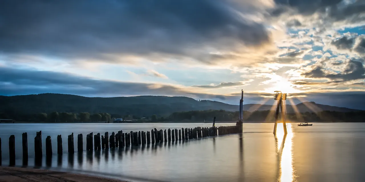 Sunlight breaking through clouds over a Pacific Northwest waterway