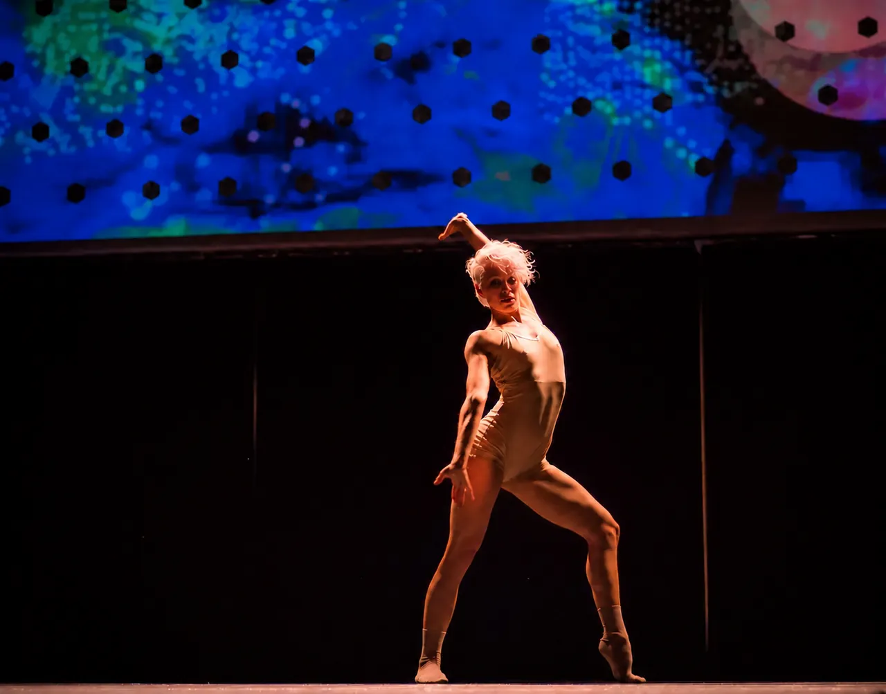 A dancer performing under dramatic stage lighting