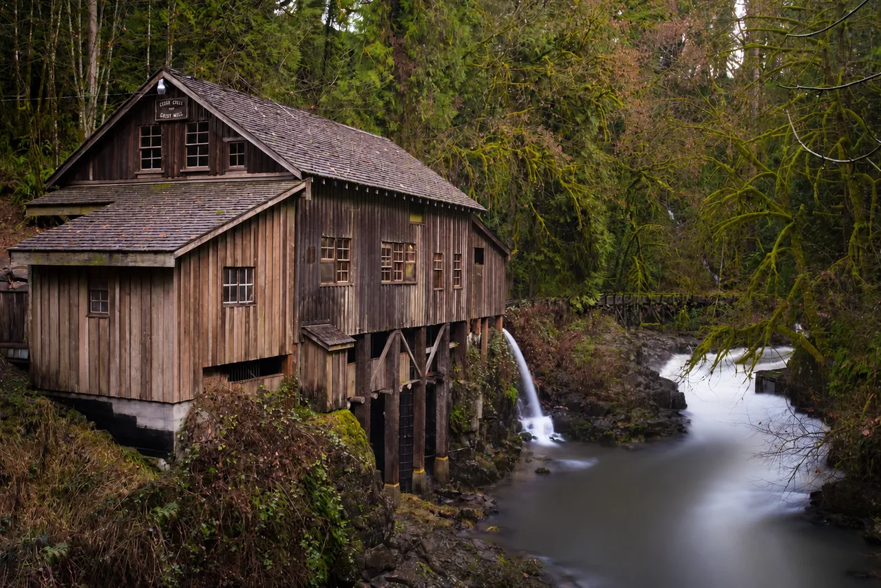 Historic Cedar Creek Grist Mill beside flowing water in a mossy forest