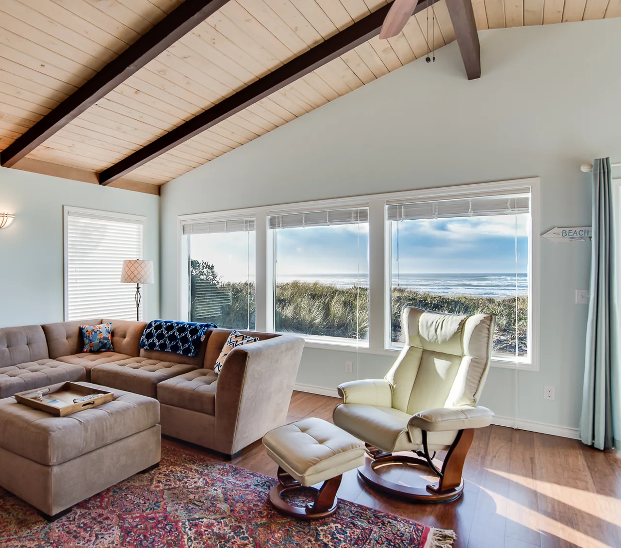 A bright ocean-view living room with a vaulted wood ceiling