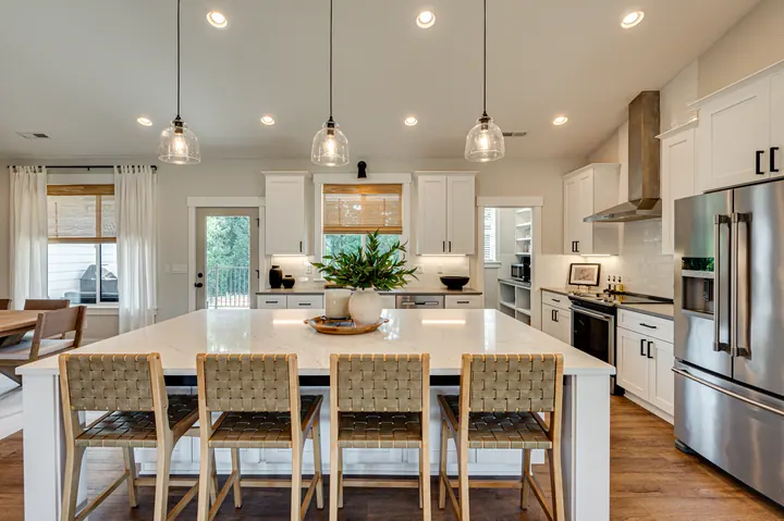 White kitchen with pendant lights and a dining island