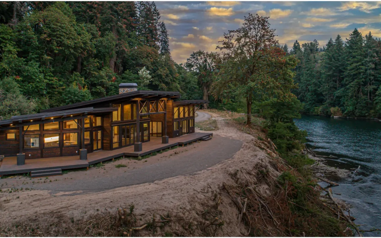 A timber residence beside a river photographed at twilight