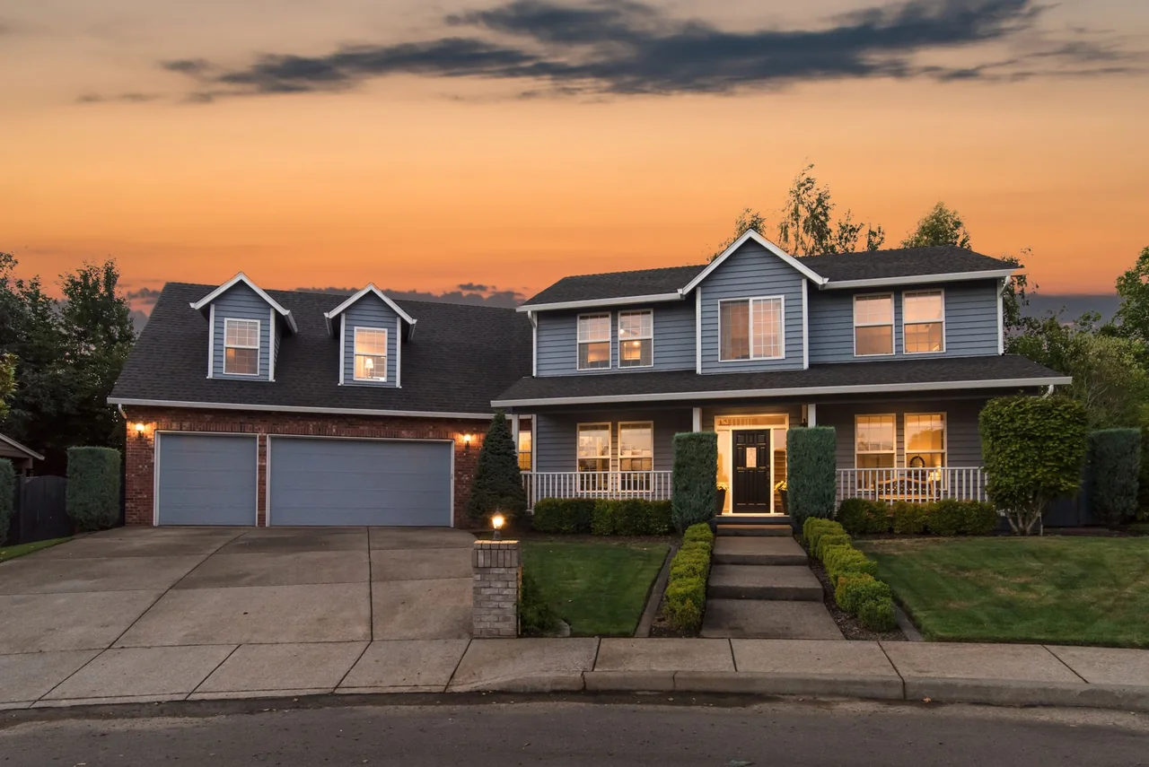 A two-story home photographed with warm interior lights at sunset